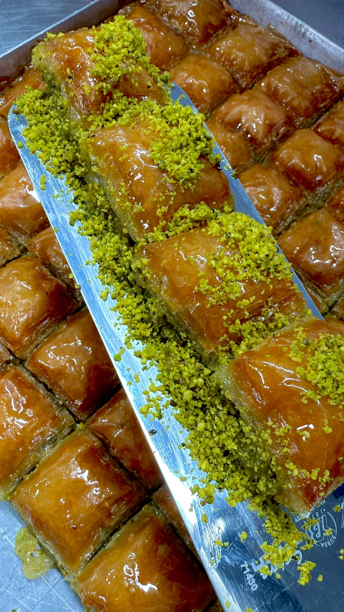 Baklava with green pistachio nuts on a metal tray