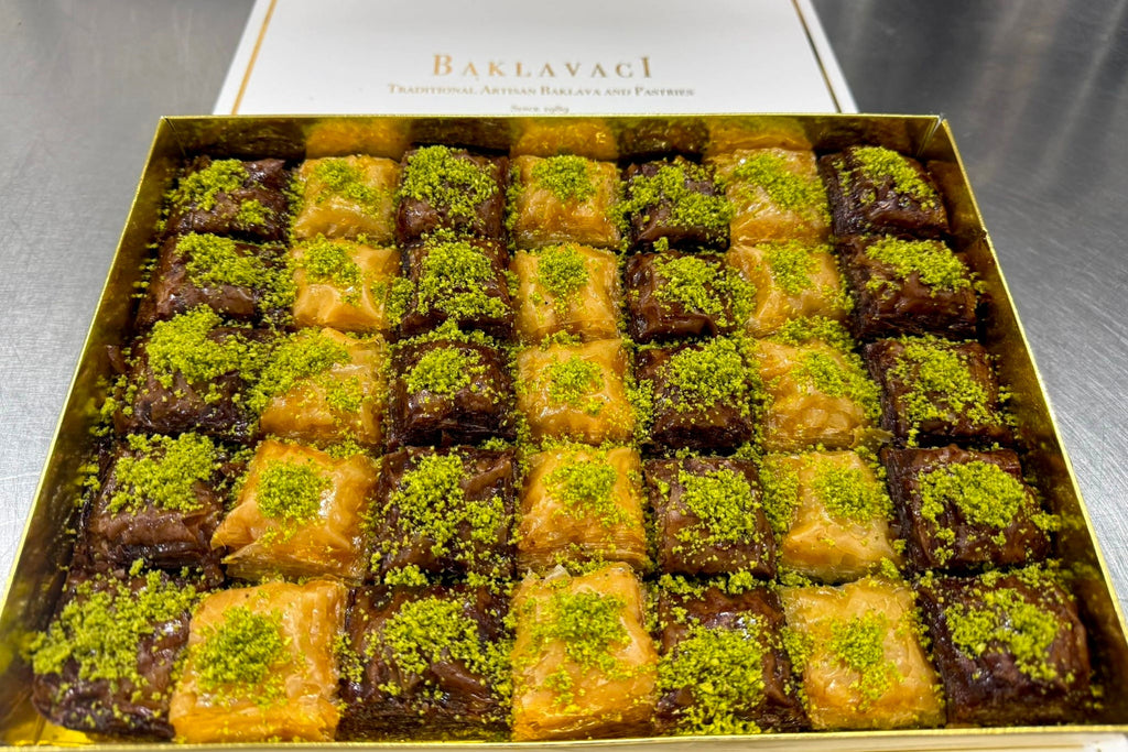 Box of assorted baklava with green pistachio on a metallic surface