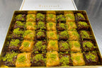 Box of assorted baklava with green pistachio on a metallic surface