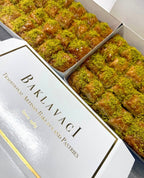 Box of baklava with green pistachio topping on a white background
