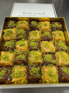 Box of baklava with green pistachio topping on a dark background