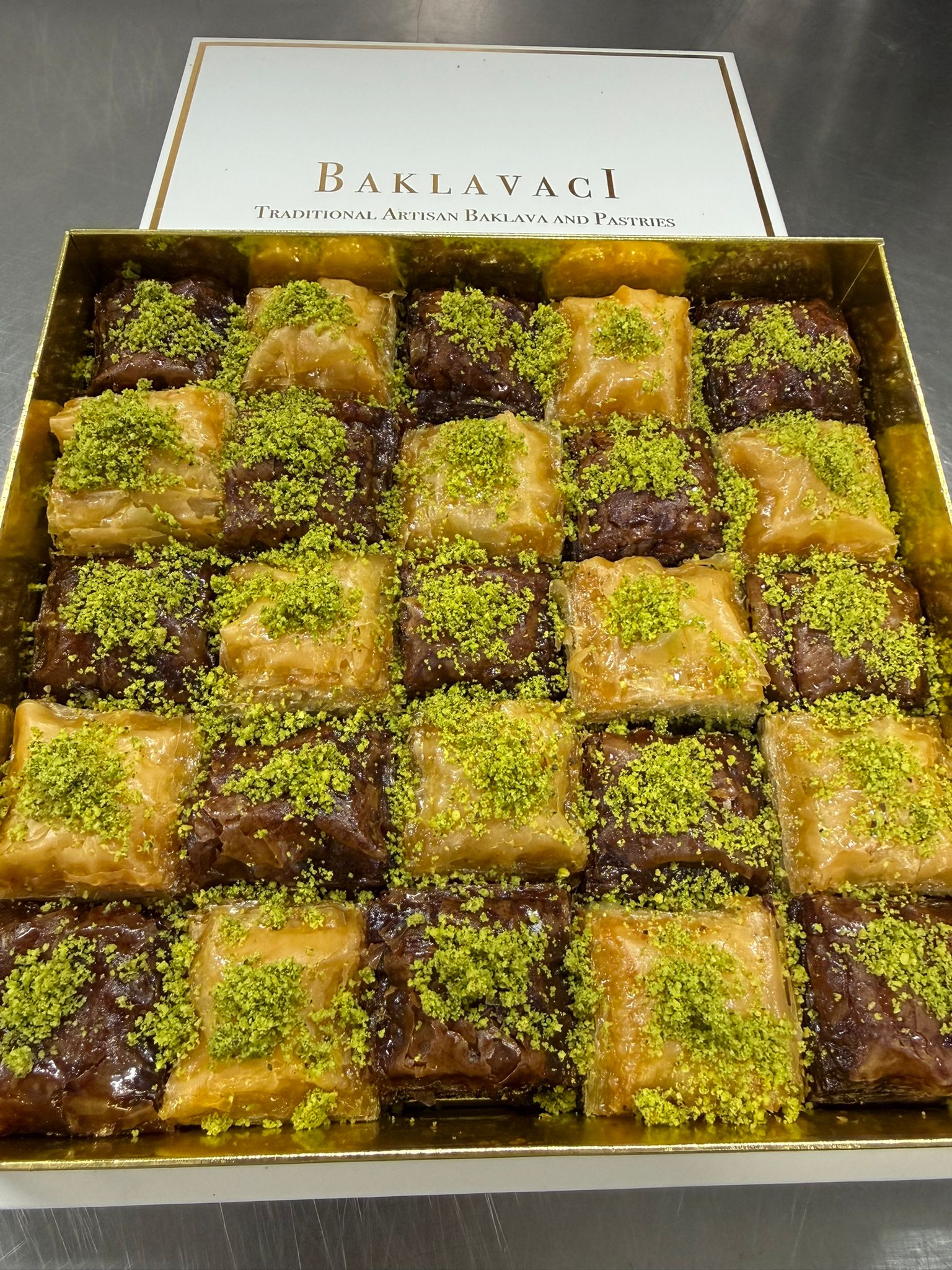 Box of baklava with green pistachio topping on a dark background