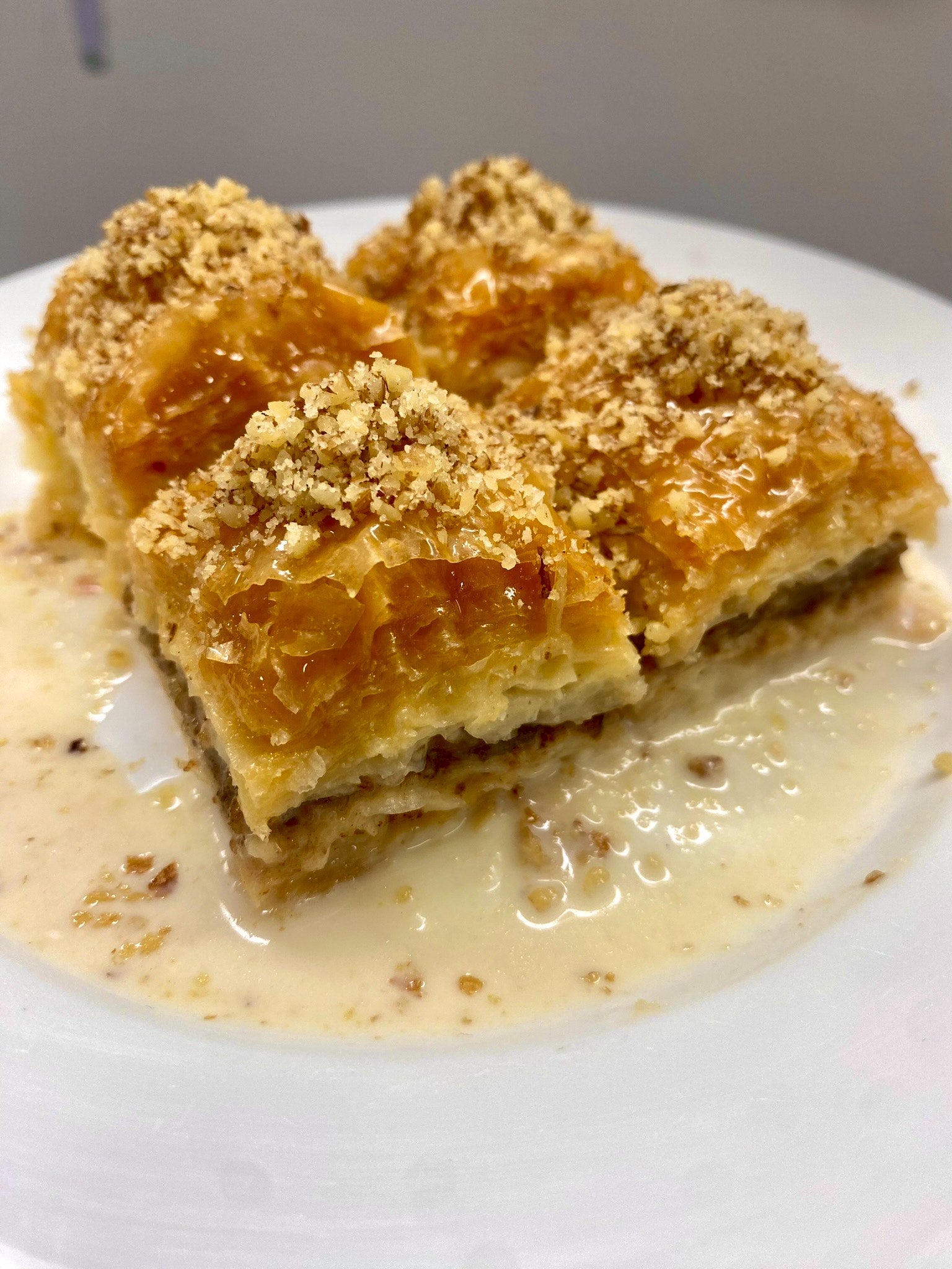 Four pieces of classic handmade walnut baklava topped with crushed walnuts and milk syrup.