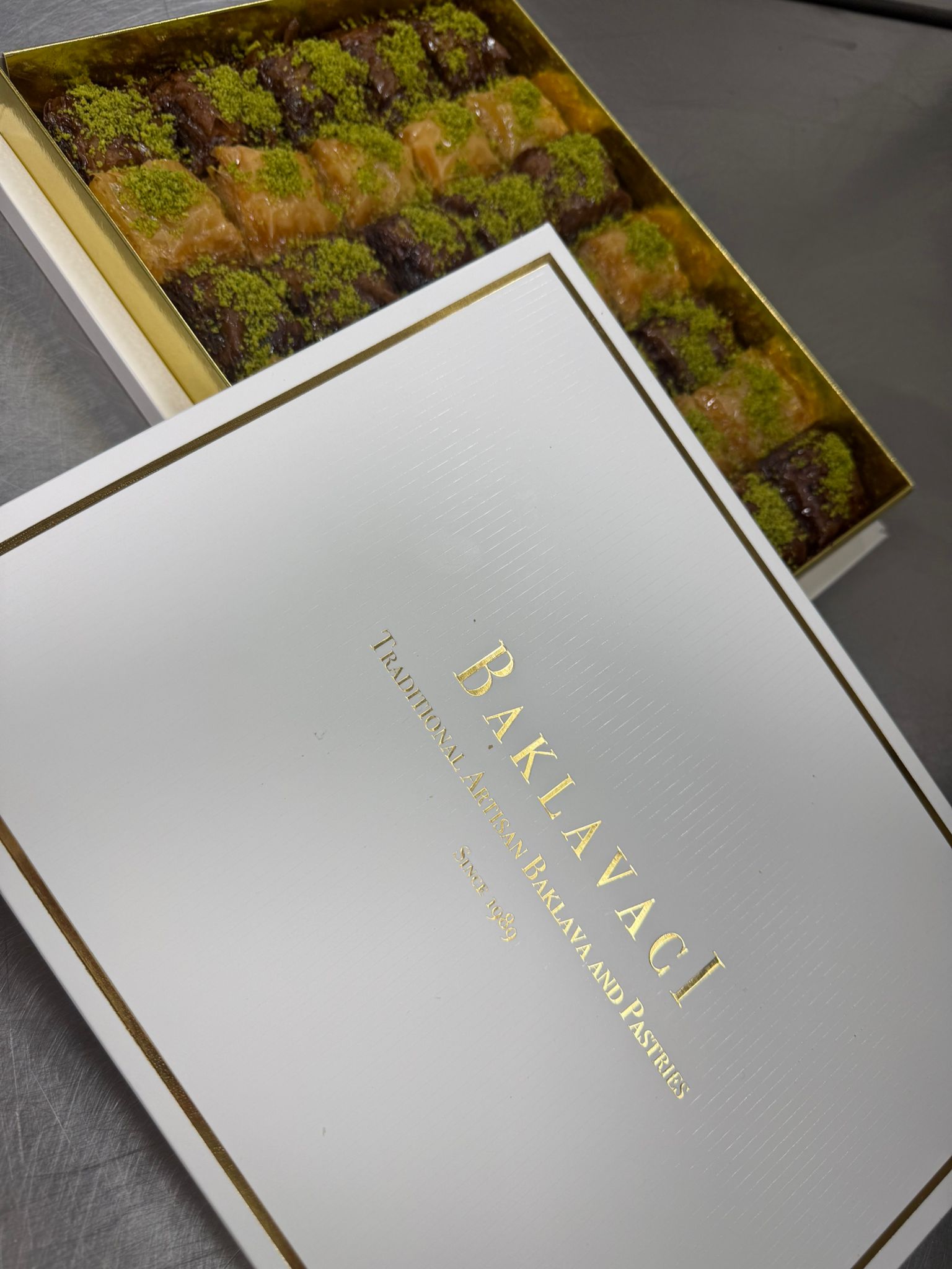 Box of baklava with a white box labeled 'Baklavaci' on a gray surface